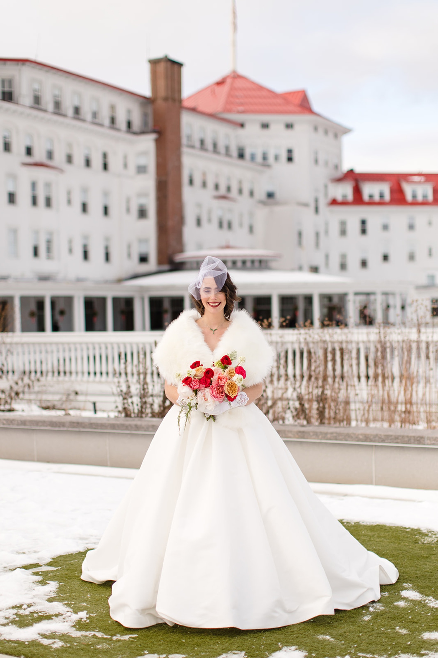 Bride in a satin ballgown and a birdcage veil with a red lip