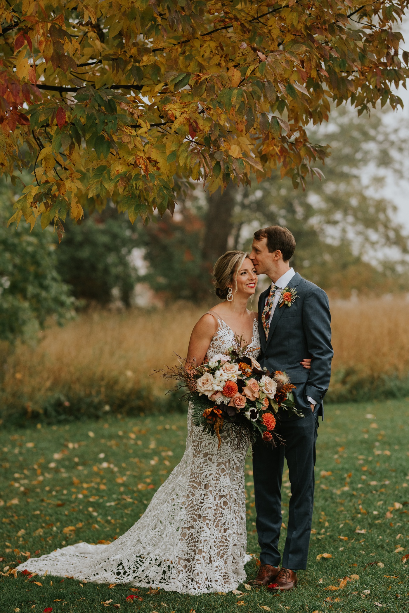 Bride holding a fall-inspired bouquet with mauve roses and orange dahlias