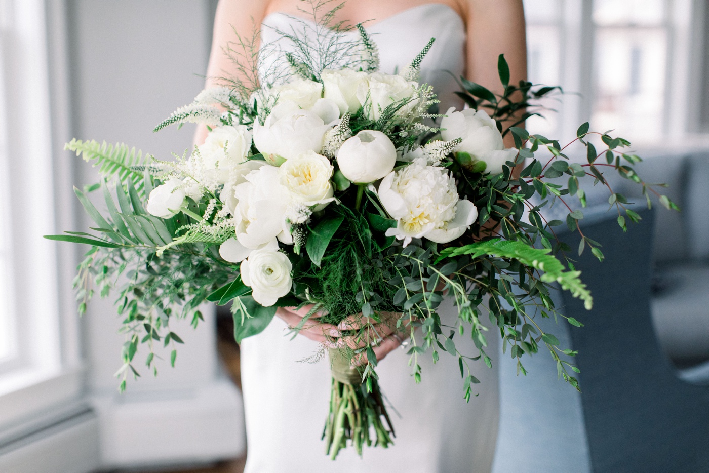 A bridal bouquet filled with white peonies and greenery by Awesome Blossom