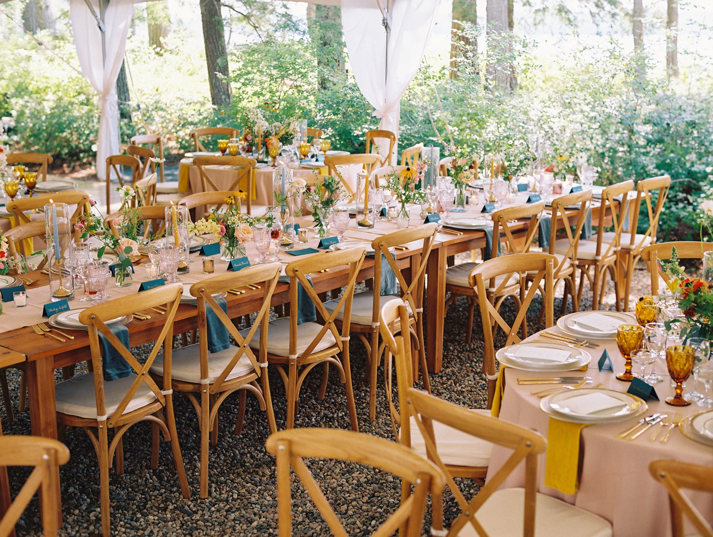 Pink tablecloths, yellow napkins, and blue place cards for a colorful wedding reception