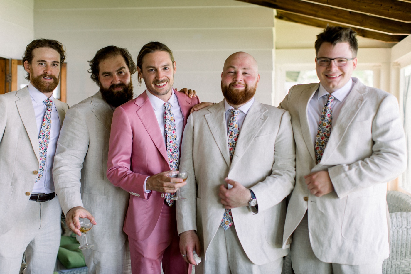 Groom wearing a pink suit with a floral necktie