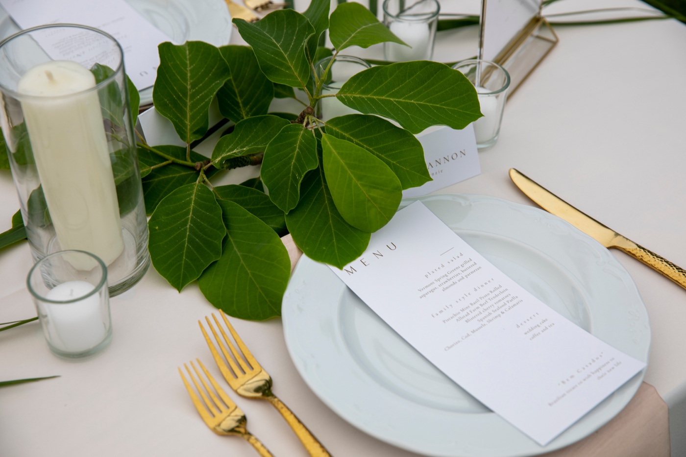 White table linens, blush napkins, and greenery for a backyard wedding reception