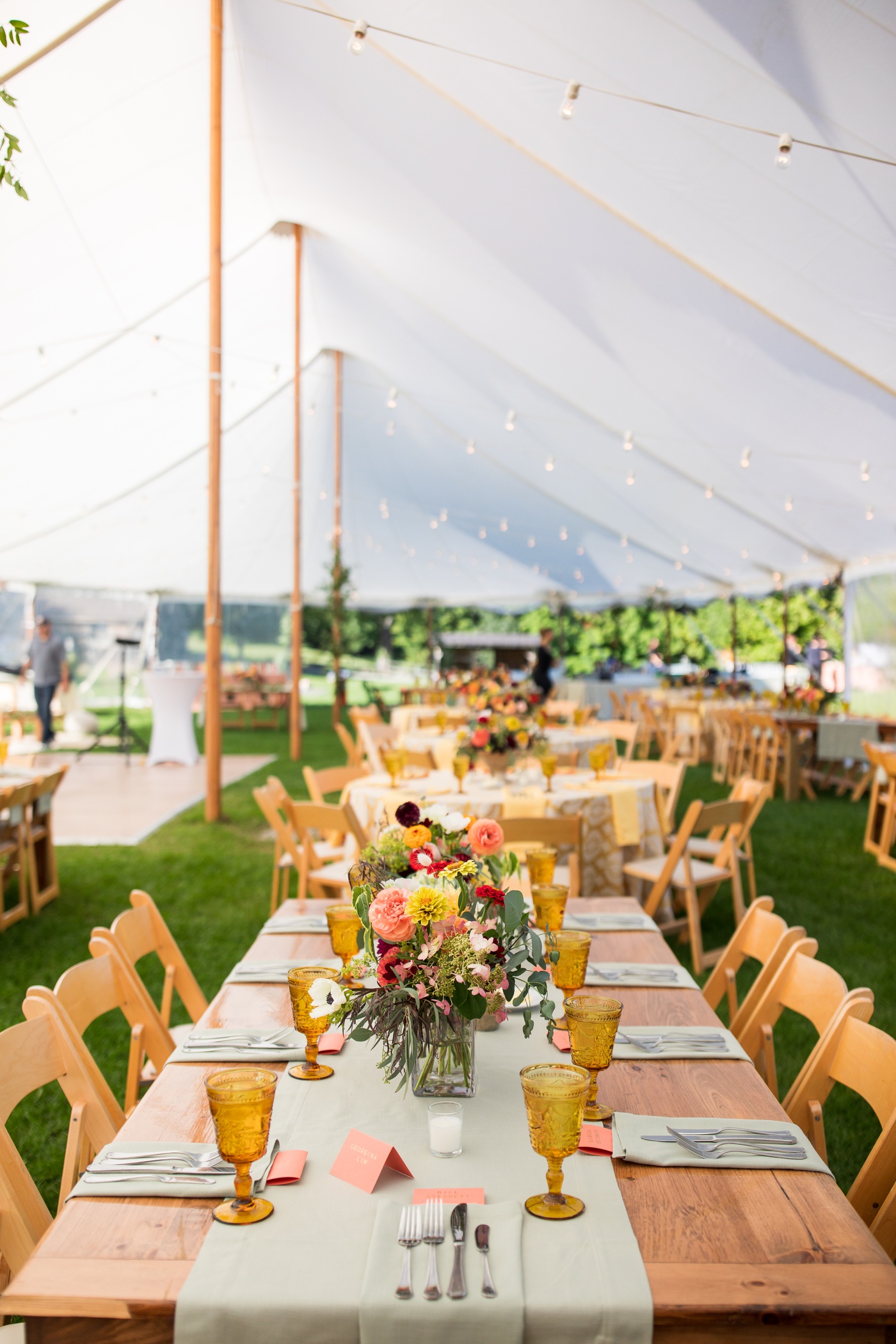 Sage linens, vintage amber goblets, and colorful floral centerpieces for a fall wedding reception