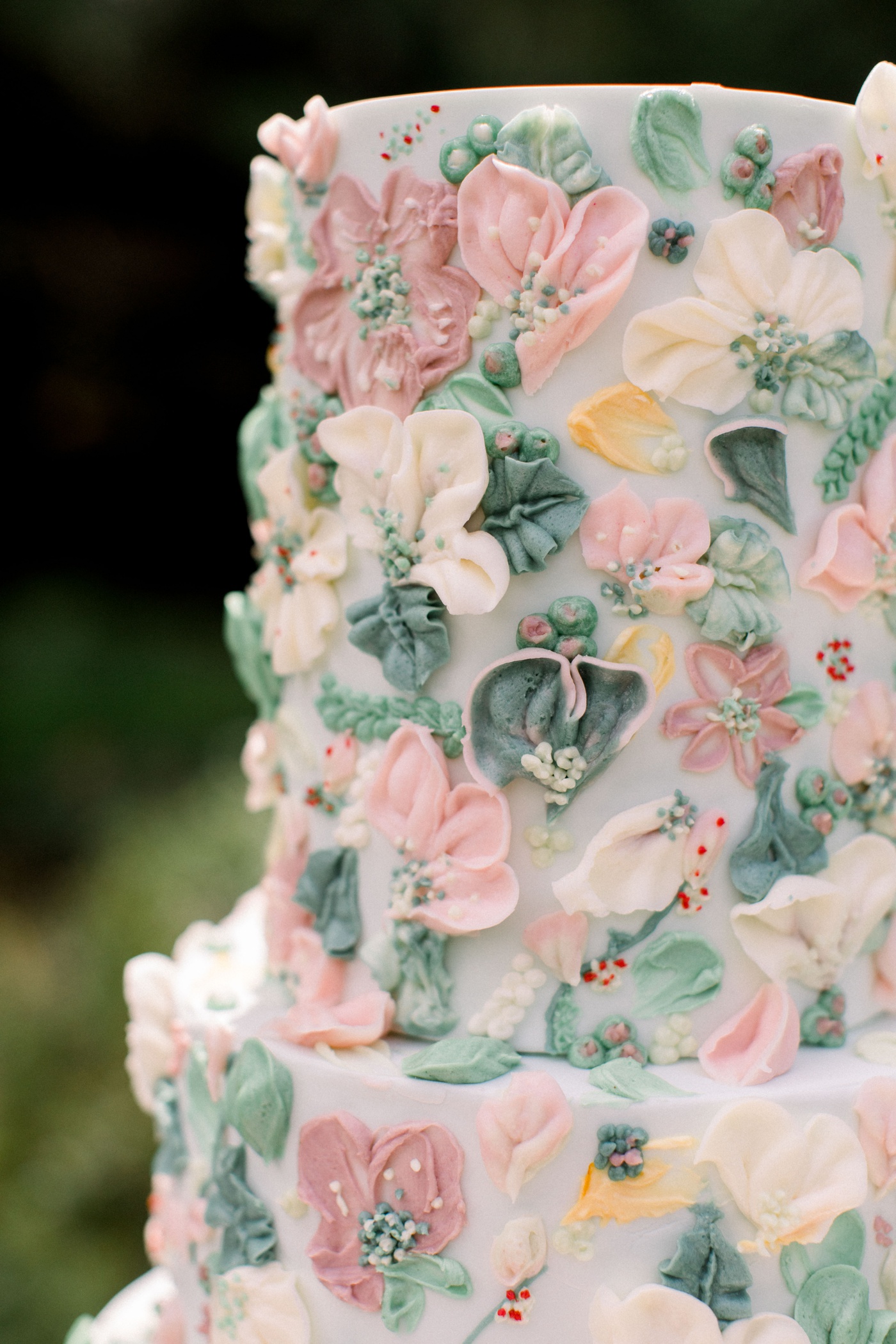 Four-tier wedding cake with frosted pink and green flowers by Eat More Cake