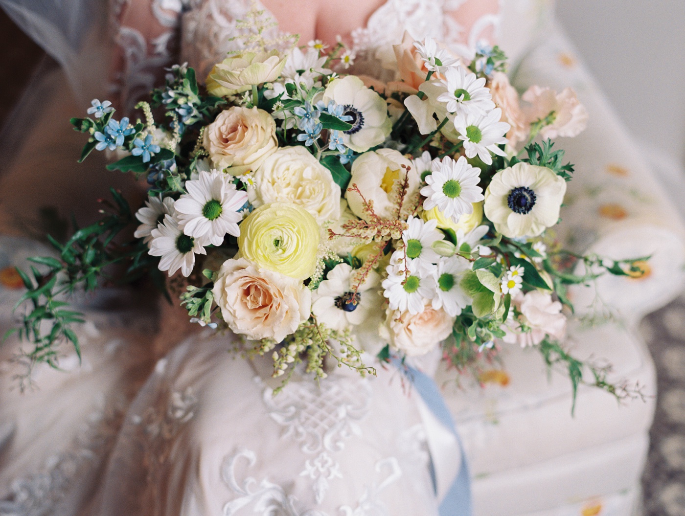 Bridal bouquet filled with anemones, daisies, blush roses, and yellow ranunculus by Emily Herzig Floral Studio